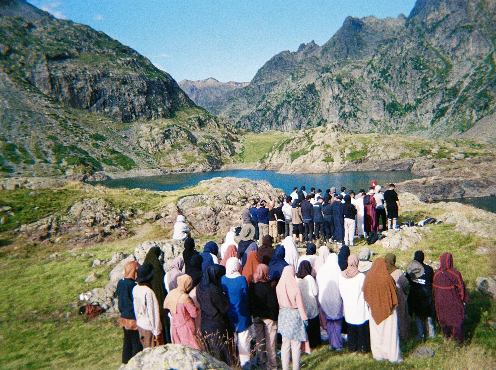 Un groupe de voyageurs prie au bord d’un lac de montagne